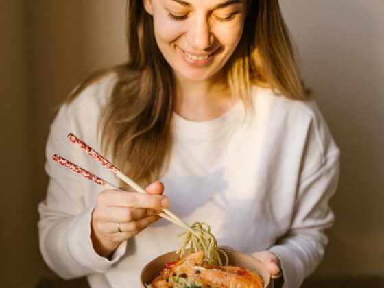 Žena uživa u zdjeli rezanaca i prakticira mindful eating, fokusirana na obrok bez distrakcija.