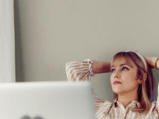 Žena sjedi uz prozor i zamišljeno gleda van, ilustracija stanja kada previše razmišljate i teško smirujete misli