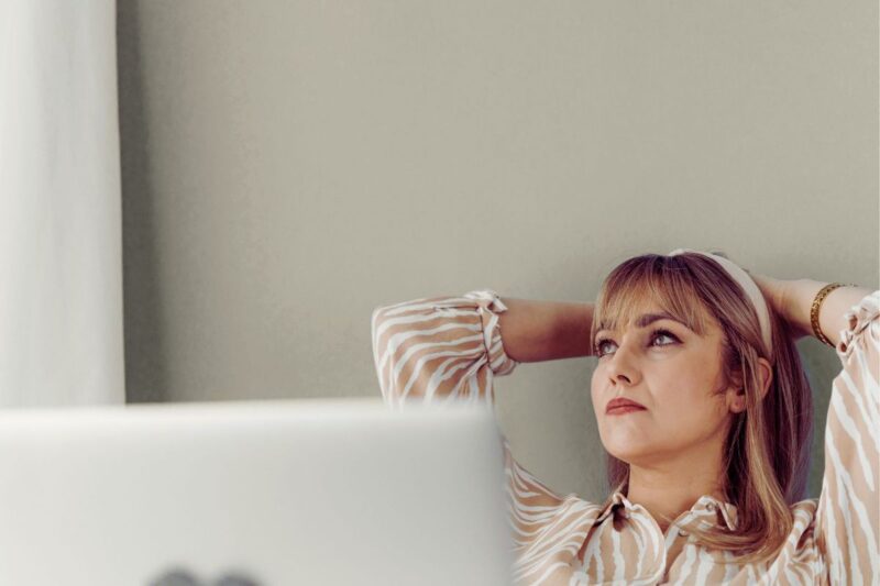 Žena sjedi uz prozor i zamišljeno gleda van, ilustracija stanja kada previše razmišljate i teško smirujete misli